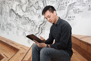 Sitting beside a BAMPFA mural project by Chinese artist Qui Zhijie, senior Andrew Wong writes in his journal. (UC Berkeley photo by Brittany Murphy)