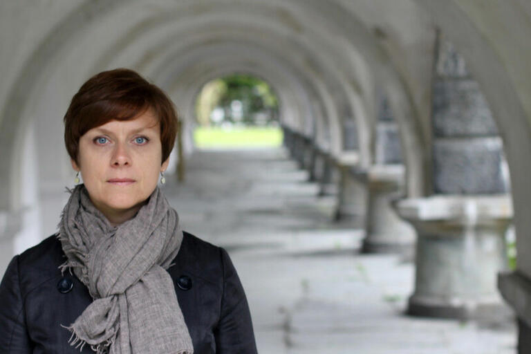 Woman standing in front of a series of stone arches.