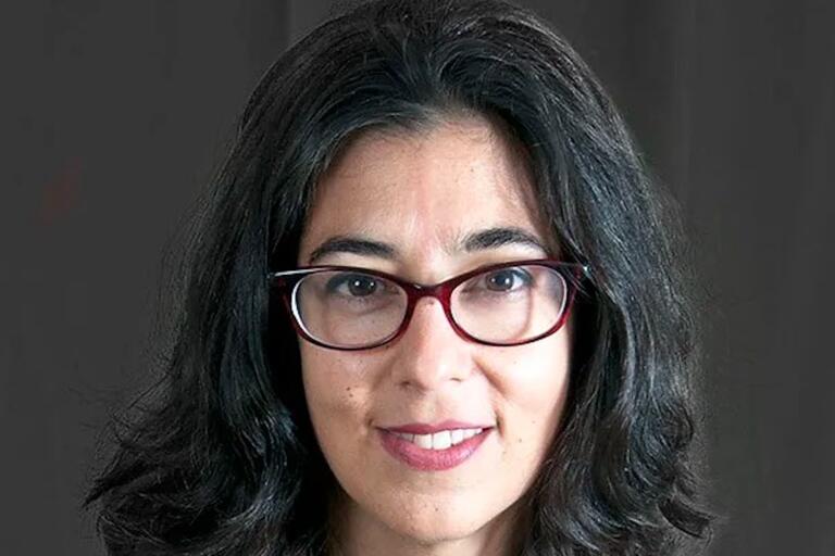 Close-up portrait of a person with dark hair and red-framed eyeglasses.