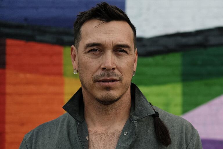 Close-up portrait of a person against a colorful mural background.