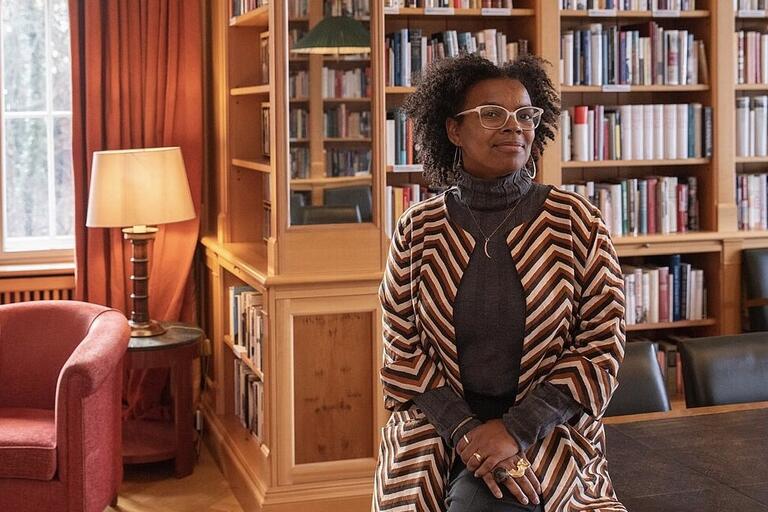 Person sitting in a library with bookshelves in the background.