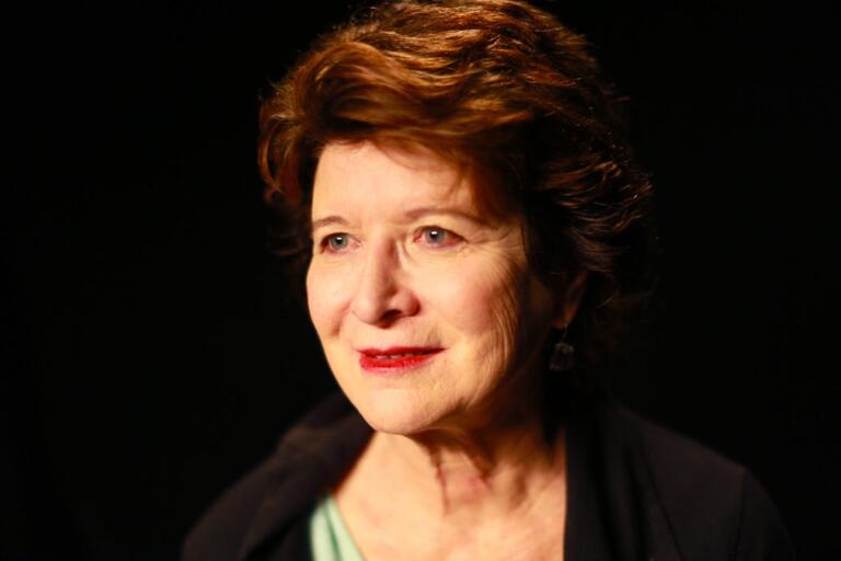 Close-up portrait of an older woman with short, wavy, dark brown hair.