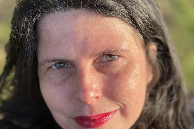 Close-up of a person's face with green eyes and red lipstick.