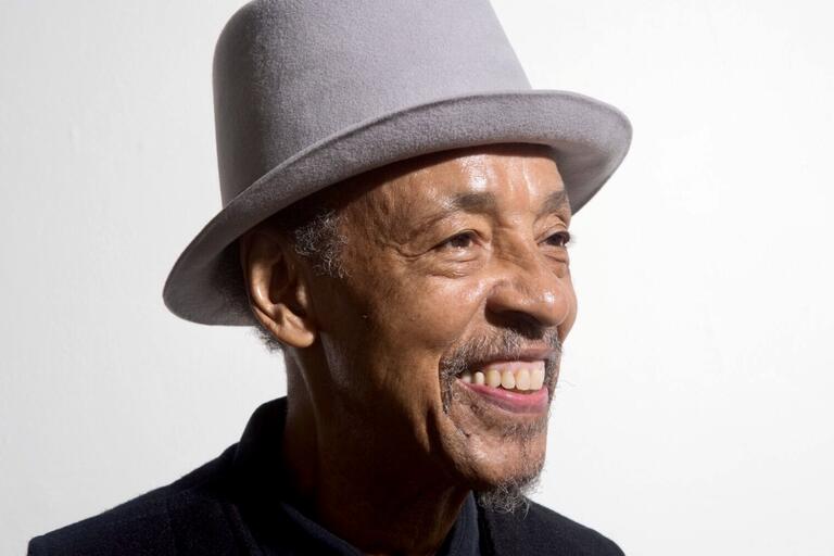 Smiling older man wearing a light gray felt hat.