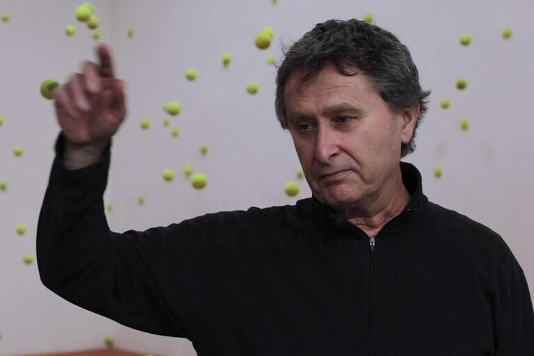 Man with raised arm amidst floating green spheres.