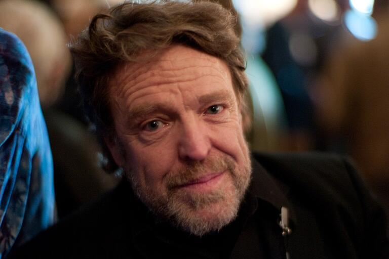 A close-up of an older man with a beard, smiling slightly at the camera.