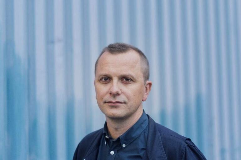Man standing in front of blue corrugated metal panels.