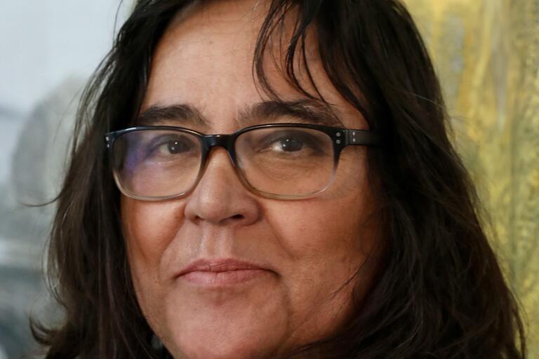 Close-up of a person with dark hair and glasses.