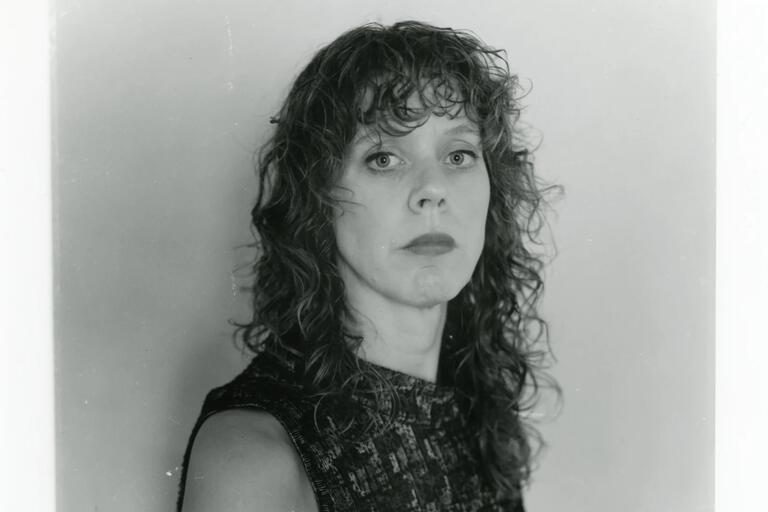 Black and white close-up portrait of a woman with curly hair and a serious expression.