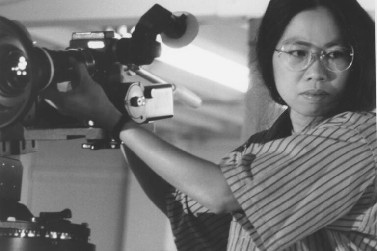 A woman operating a professional video camera indoors.