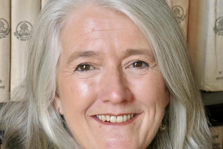 Close-up portrait of a person with light gray hair, smiling.