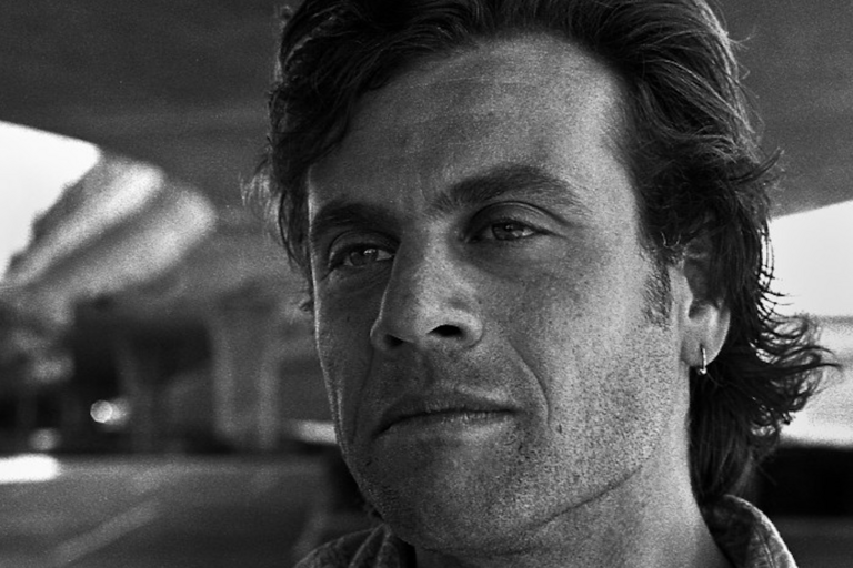 Close-up black-and-white portrait of a contemplative man with medium-length hair and an earring.