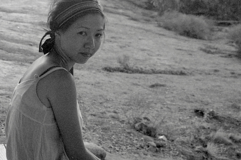 Black-and-white photo of a person with a headband sitting on a rocky terrain.