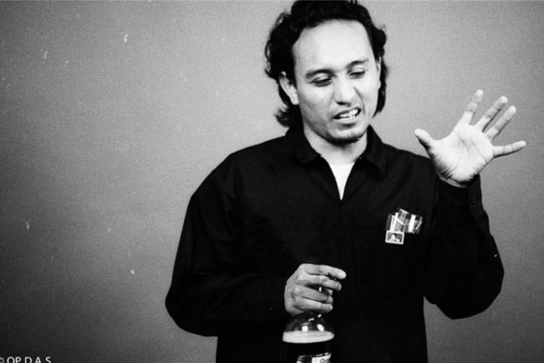 Person holding a bottle and gesturing with their hands in a black-and-white photograph.