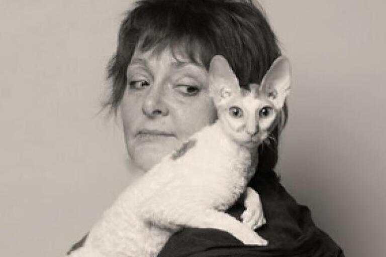 A black-and-white portrait of a woman with short hair and a white cat on her shoulder.