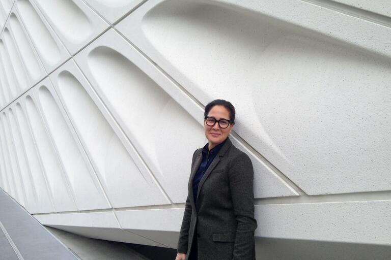 Person standing against a wall with a geometric, hexagonal pattern.