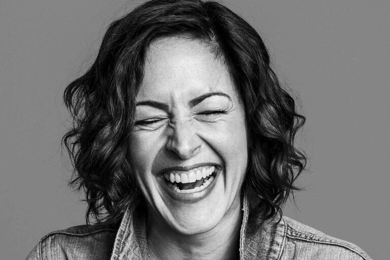 Black-and-white close-up photo of a person laughing with eyes closed.