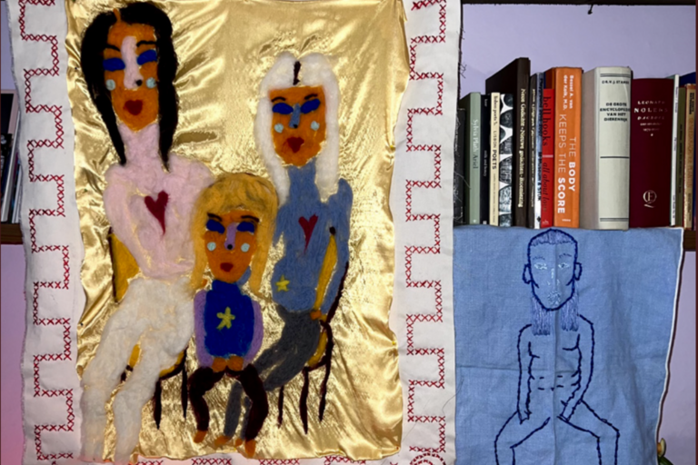 embroidery of 3 people hanging in front of a bookshelf