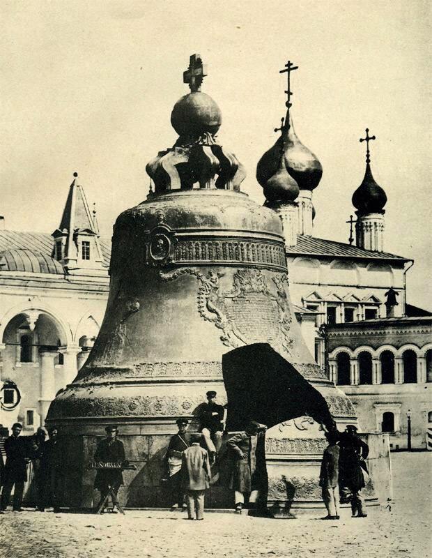 Old photo of giant bell with men resting around it