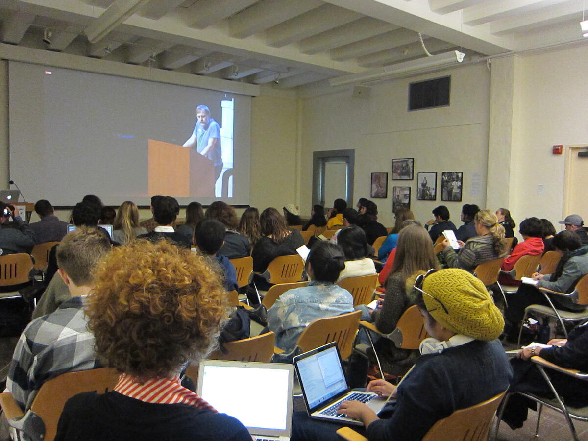 Students watching livestream of man talking at lectern
