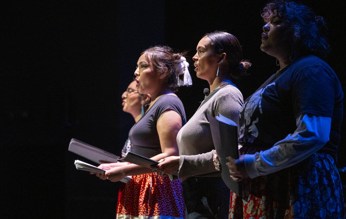 Four young people stand singing with scripts in hand