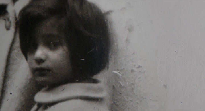 film still of young child looking nervously at the camera, blurry and black & white