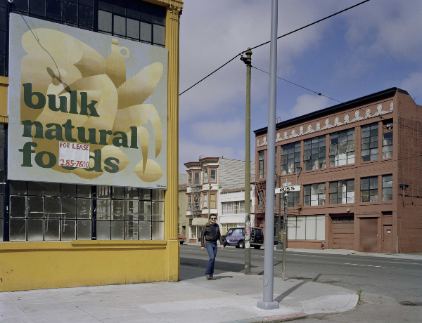 Photo of street corner in San Francisco. There is a yellow building for lease