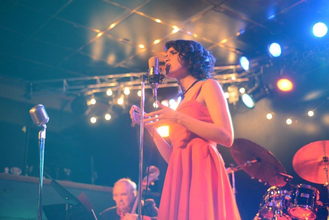 women in red dress at a microphone singing