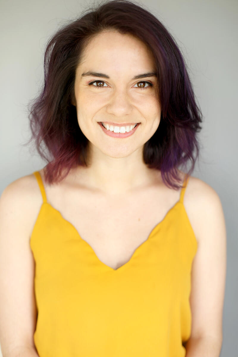 brunette woman with yellow shirt against light gray background