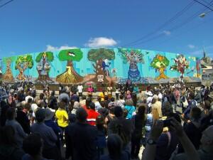 A Crowd gathers around a mural of trees