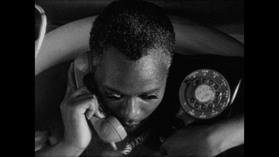 Film still of man talking into an old-fashioned telephone, black & white