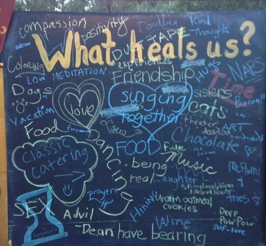 Chalkboard covered in multi-colored writing, with the prompt "What heals us?"
