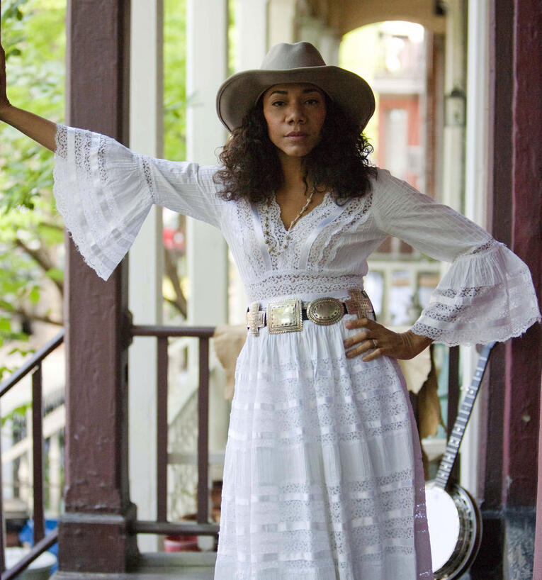 Women in a white dress and white hat with hand on hip