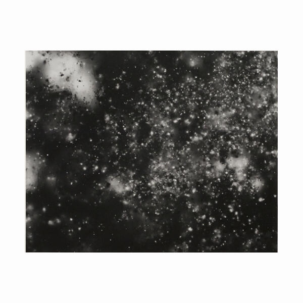  Abstract black and white image with small white specks scattered on a dark background, resembling a star field.