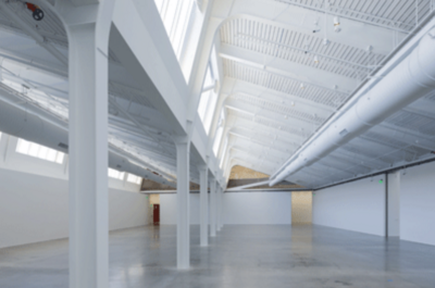 Spacious industrial interior with high ceiling, skylights, and polished concrete floor.