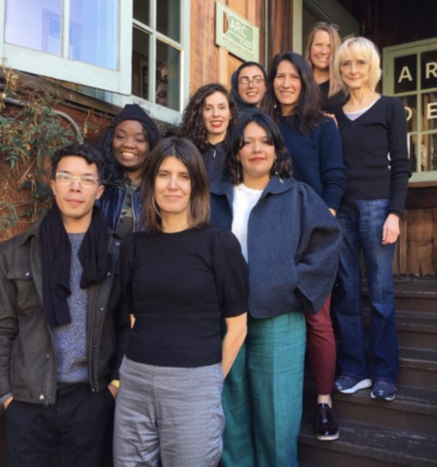 Nine people standing on wooden steps in front of a building with a sign that reads "ARC."